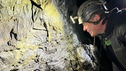 Höhlenforscher Stefan Voigt in einer Höhle vor einer Versteinerung