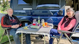 Susanne und Alfons Mause sitzen beim Frühstück an ihrem Camper.