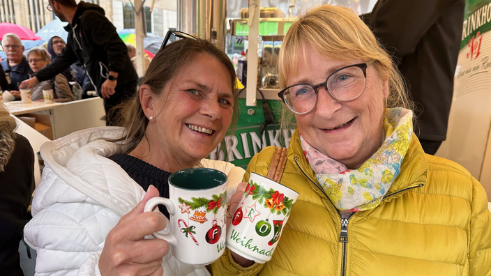 Zwei lächelnde Frauen mit Tassen in der Hand