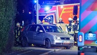 Feuerwehrleute stehen bei dem Unfallauto