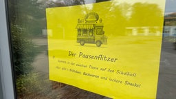 Ein gelber Zettel klebt an einer Glaswand an der Gesamtschule Hattingen-Welper, darauf wird für den "Pausenflitzer" geworben