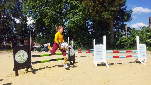 Jette springt mit ihrem Steckenpferd Milo über ein Hindernis beim Hobby Horsing Cup in Hattingen.