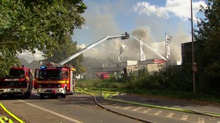 Zwei Feuerwehrwagen löschen eine verrauchte Halle