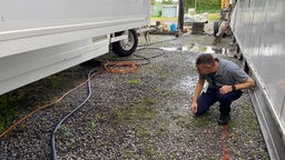 Der Platzmeister sucht einen Hydranten unter einem Wohnwagen