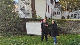 Zwei Personen stehen vor einem Tiny-House. 