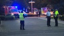 Blaulicht, Rettungswagen und Feuerwehr auf einem Parkplatz, mehrere Leute stehen davor