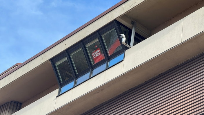 In einer Fensterfront hängt ein Plakat mit dem Schriftzug Warnstreik in Großbuchstaben. 