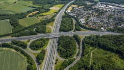 Auf dem Foto ist das Westhofener Autobahnkreuz aus einer Vogelperspektive. Flankiert wird es von Schwerte-Westhofen und Waldgebieten.