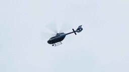 Auf dem Bild ist ein Polizeihubschrauber zu sehen, der über dem Einsatzort fliegt.