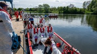 Menschen in Schutzanzügen sitzen in einem Boot auf dem Wasser