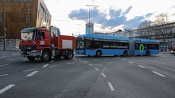 Ein Feuerwehrauto zieht einen blauen Linienbus hinter sich her.