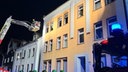 zu sehen ist ein Mehrfamilienhaus und Feuerwehrleute