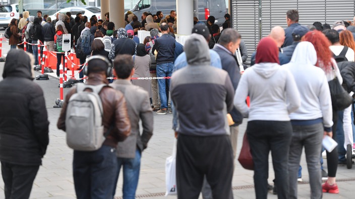 Eine Schlange an Menschen vor der Ausländerbehörde Frankfurt