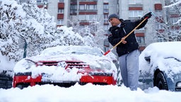 Ein Mann befreit sein Auto von Schnee