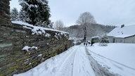 Schnee bedeckt einen Weg entlang einer alten Mauer