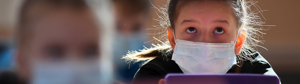 Mädchen mit Mundschutz schaut auf ein Tablet (Ivanovo, Russland)