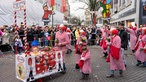 Teilnehmende des Schull- un Veedelszöchs ziehen mit einem kleinen Wagen kostümiert durch die Straßen