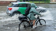 Eine Radfahrerin ist bei Starkregen unterwegs.