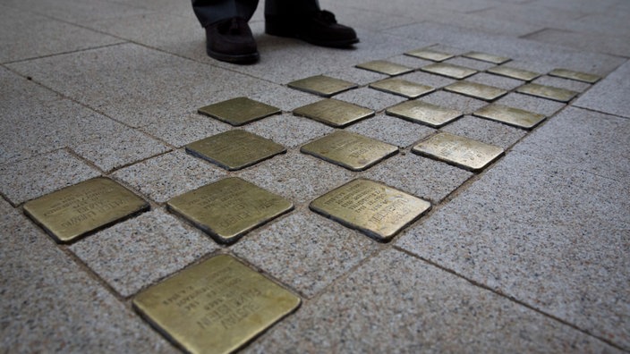 Ein Passant betrachtet Stolpersteine.