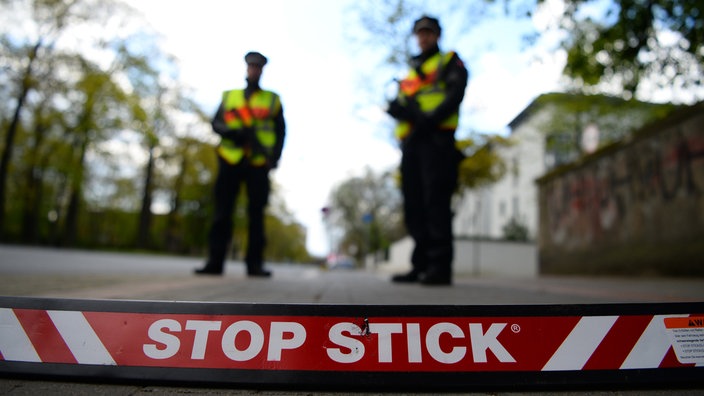  Polizisten stehen hinter einem sogenannten Stop Stick - einer modernen Art von Nagelsperre.