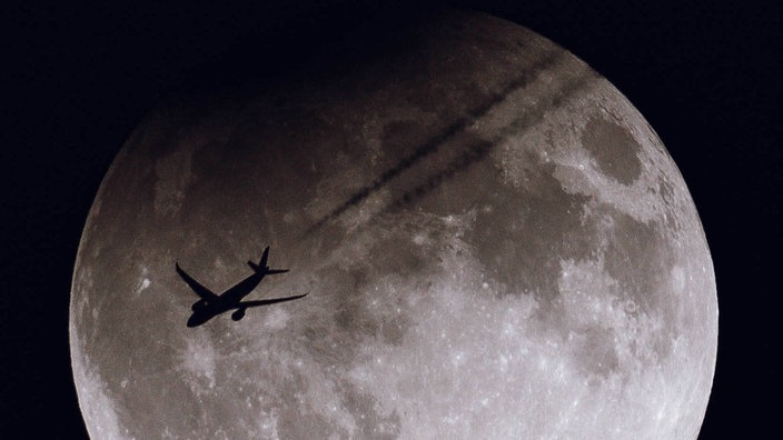 Ein Passagierflugzeug fliegt vor dem Supermond 