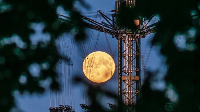 Der Vollmond scheint hinter dem Hochkarusell auf dem Oktoberfest in München