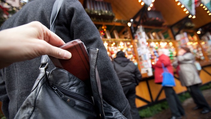 Ein Taschendieb klaut einen Geldbeutel aus deiner Tasche auf einem Weihnachtsmarkt