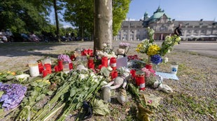 Blumen, Kerzen und handgeschriebene Trauerbekundungen stehen an einem Baum im Kurpark Bad Oeynhausen