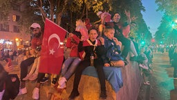 Türkische Fans feiern auf den Kölner Ringen trotz Niederlage im EM-Viertelfinale gegen die Niederlande. Zwei Menschen zeigen den Wolfsgruß