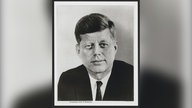 Offizielles Porträt von US-Präsident Kennedy: Schwarz-Weiß-Foto eines Mannes in Anzug, der nachdenklich in die Kamera schaut