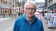 Ein Mann mit weißem Schnurrbart und blauer Jacke