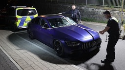 Ein beschädigter Mercedes AMG steht nach einem Unfall auf einer Straße in Remscheid Lennep. Polizeibeamte sichern Spuren an dem Fahrzeug.