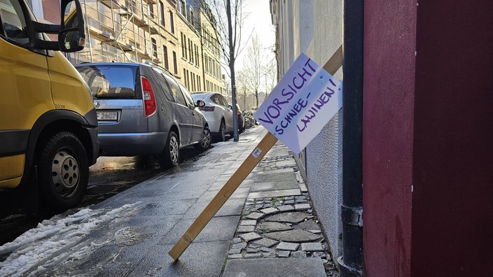 Selbstgebasteltes Schild mit der Warnung vor Schneelawinen auf einem Gehweg