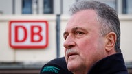 Claus Weselsky im Vordergrund, im Hintergrund Logo der Deutschen Bahn