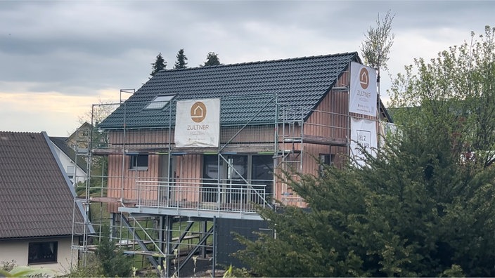 Haus aus Borkenkäferholz mit Gerüst