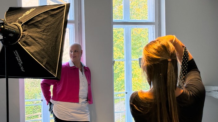 Anke Theiler posiert vor einem Fenster und wird von Nadine Marga-Fahrenkamp fotografiert