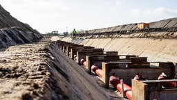 Die Baustelle der Stromtrasse, im Hintergrund ein Mensch in Warnweste.