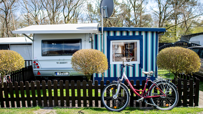 Campingwagen mit Anbau, Zaun und Fahrrad 