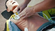 Übung einer Wiederbelebung mit Defibrillator und Puppe