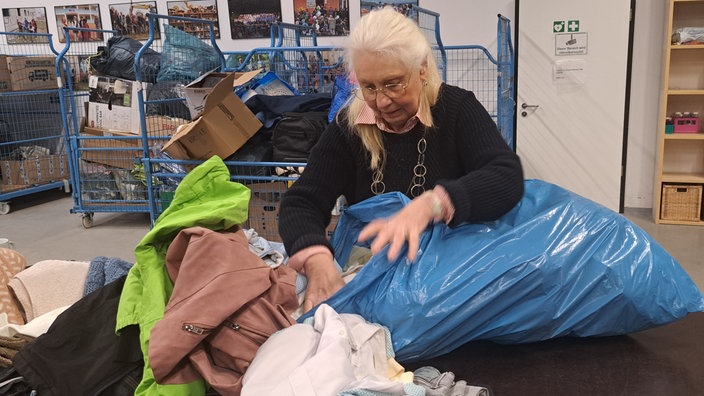 Eine Frau, die einen Blauen Sack mit Spenden durchschaut.