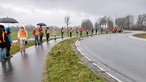 Die Friedesnkette auf dem Gehweg an einer Landstraße.