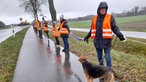 Teilnehmende auf einem Gehweg an einer Landstraße.