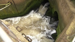 Blick auf offene Abwasserrohre, die in ein Becken münden, schmutziges Wasser sprudelt stark