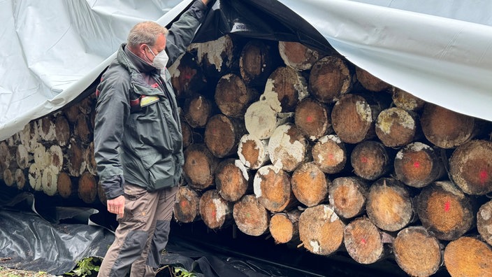 Mann öffnet Folienlager von Holz in Arnsberg.