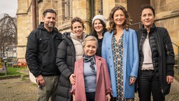 Sechs Menschen posieren vor einer Kirche für ein Foto.