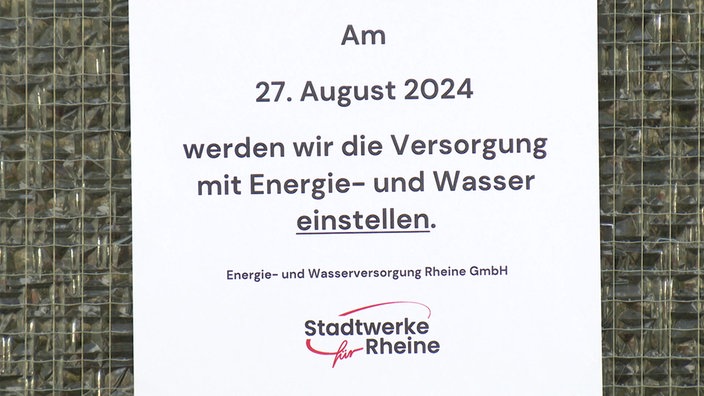 Es ist ein weißer Zettel zu sehen auf dem gedruckt steht: "Am 27. August werden wir Versorgung mit Energie und Wasser einstellen."