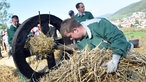 Männer stopfen ein Holzrad mit Stroh