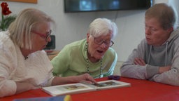 Kathrin, Edith und Gitti (v.l.n.r.) betrachten ihr Fotoalbum