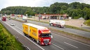 Auf dem Foto ist eine dreispurige Autobahn mit einem Rastplatz mit einem großen Lkw-Parkplatz und einer Tankstelle.