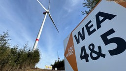 Auf dem Bild ist ein Windrad und Hinweisschild für den Windpark zu sehen.